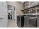 This laundry room boasts stainless steel washer and dryer units and a view to the powder room at 2148 W Angelo Way, San Tan Valley, AZ 85144