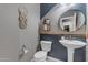 This stylish powder room features blue accent walls, a round mirror, and pedestal sink at 2148 W Angelo Way, San Tan Valley, AZ 85144