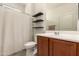 Modern bathroom featuring floating shelves, wooden vanity, and shower/tub combo at 27418 W Mohawk Ln, Buckeye, AZ 85396