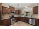 Updated kitchen with stainless appliances, tiled floors, and granite countertops and brown cabinets at 3277 E Meadowview Dr, Gilbert, AZ 85298
