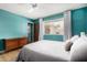 Cozy bedroom bathed in bright turquoise features hardwood floors, natural light, and ceiling fan at 3536 W Cholla St, Phoenix, AZ 85029