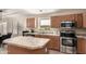 Kitchen featuring a center island, stainless steel appliances, and warm wood cabinets at 42277 W Chisholm Dr, Maricopa, AZ 85138
