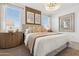 Inviting bedroom showcasing an elegant chandelier, a wood accent wall, and natural light at 46422 W Lander Ln, Maricopa, AZ 85139