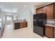 Open kitchen featuring tile floors, wood cabinets, granite countertops, and black appliances at 6815 W Carter Rd, Laveen, AZ 85339
