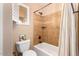 Well-lit bathroom featuring a bathtub with tiled walls and a window, alongside a toilet at 7039 W Katharine Way, Peoria, AZ 85383