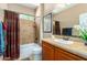 Well-lit bathroom featuring a bathtub, shower with patterned curtain, and a single sink vanity with tile countertop at 7039 W Katharine Way, Peoria, AZ 85383