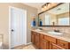 Well-lit bathroom with double sinks, framed mirror, decorative tile backsplash, and neutral-toned walls at 7039 W Katharine Way, Peoria, AZ 85383