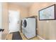 Convenient laundry room featuring a white washer and dryer set next to the door and a storage shelf at 7039 W Katharine Way, Peoria, AZ 85383
