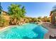Backyard pool with cascading waterfall feature, lush landscaping, and patio seating, creating a tranquil outdoor oasis at 7039 W Katharine Way, Peoria, AZ 85383