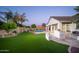 This home's backyard features a pristine artificial lawn, a built-in BBQ, and mature landscaping at 7590 W Firebird Dr, Glendale, AZ 85308