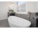 Modern bathroom featuring a freestanding tub, black vanity, and plantation shutters at 7590 W Firebird Dr, Glendale, AZ 85308