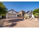 Charming home with desert landscaping, a brick driveway, a two-car garage, and solar panels on the roof at 7590 W Firebird Dr, Glendale, AZ 85308