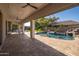 The covered patio provides ample space for outdoor lounging overlooking the backyard and rock waterfall pool at 7590 W Firebird Dr, Glendale, AZ 85308