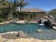 Backyard pool area features a rock waterfall, desert landscaping, and a tanning ledge at 7590 W Firebird Dr, Glendale, AZ 85308