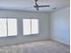 Spacious bedroom with neutral carpet, a ceiling fan, and large windows for natural light at 7925 S 52Nd Dr, Laveen, AZ 85339