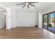 Open-concept living room with wood floors, ceiling fan, and sliding glass doors to backyard at 7925 S 52Nd Dr, Laveen, AZ 85339
