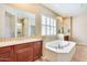 Bright bathroom with a soaking tub, and dark wood cabinets with granite countertops at 795 W Verbena Ln, Litchfield Park, AZ 85340