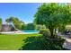 Lush backyard with artificial turf, a pool, mature trees, and lush landscaping, offering a private oasis at 8419 E Stella Ln, Scottsdale, AZ 85250