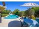 Backyard pool with a slide and lush landscaping with a dining table and chairs under an umbrella for outdoor relaxation at 8419 E Stella Ln, Scottsdale, AZ 85250