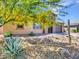 Charming single-story home featuring desert landscaping, a stone driveway, and vibrant yellow flowering trees at 9253 W Sands Dr, Peoria, AZ 85383