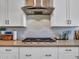 Modern kitchen features a stainless steel range hood, herringbone tile backsplash, and white cabinetry at 9253 W Sands Dr, Peoria, AZ 85383