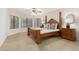 Main bedroom with a four poster bed frame, tan carpet, and multiple windows at 9809 W Behrend Dr, Peoria, AZ 85382