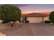 Charming home with a two-car garage, desert landscaping, and a red tile roof in front of a colorful sunset at 9809 W Behrend Dr, Peoria, AZ 85382