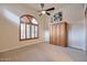 Bedroom features arched window, neutral carpet, ceiling fan and a large, wooden wardrobe at 9847 E Preserve Way, Scottsdale, AZ 85262