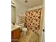 Well-maintained bathroom featuring tile flooring and a charming floral shower curtain at 10705 W Montecito Ave, Phoenix, AZ 85037