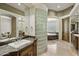 Luxurious bathroom with dual sinks, travertine floors, glass block and a soaking tub at 11717 E Estrella Ave, Scottsdale, AZ 85259