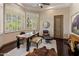 Inviting home office with wood desk, comfortable seating, and natural light from large windows at 11717 E Estrella Ave, Scottsdale, AZ 85259