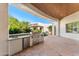 Beautiful outdoor kitchen with built in stainless steel grill, mini refrigerator, and stone patio at 11717 E Estrella Ave, Scottsdale, AZ 85259