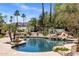 Backyard pool featuring rock waterfalls, lush landscaping, palm trees, and a tranquil ambiance at 11717 E Estrella Ave, Scottsdale, AZ 85259