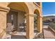 Inviting front porch with stone arches features seating and a decorative glass front door at 17874 N 93Rd Way, Scottsdale, AZ 85255