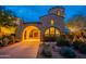 Inviting home exterior showcasing a unique turret design and well-lit entrance, perfect for evening enjoyment at 18283 N 93Rd St, Scottsdale, AZ 85255