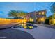 Back of a two-story home featuring outdoor lighting, a private pool with rock accents, a wood deck and lush landscaping at 18283 N 93Rd St, Scottsdale, AZ 85255