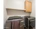 Modern laundry room features newer appliances, a mounted cabinet and floating shelf for convenient storage and organization at 18283 N 93Rd St, Scottsdale, AZ 85255