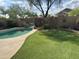 Private backyard features a refreshing pool with a rock waterfall feature, complemented by lush green turf and block fence at 2138 E Williams Dr, Phoenix, AZ 85024