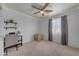 This is a bright bedroom with a ceiling fan, plush carpeting, a window, and simple decor at 23693 W Grove St, Buckeye, AZ 85326