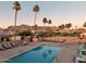 Community pool with mountain views, lounge chairs, tables, and desert landscaping at 2400 E Baseline Ave # 71, Apache Junction, AZ 85119