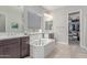 Bright bathroom featuring a soaking tub, dual vanities, and a walk-in closet, creating a serene space at 29403 N 119Th Ln, Peoria, AZ 85383