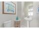 Charming powder room with pedestal sink, decorative artwork, and woven basket storage at 29403 N 119Th Ln, Peoria, AZ 85383
