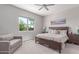 Bedroom featuring a wooden bed frame, a plush loveseat, and a sunny window with green outdoor views at 29403 N 119Th Ln, Peoria, AZ 85383