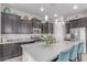 Modern kitchen with dark cabinets, stainless steel appliances, a spacious island with seating, and pendant lighting at 29403 N 119Th Ln, Peoria, AZ 85383