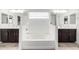 A white bathtub is centered between two dark wood vanities with double mirrors, creating a spacious and clean bathroom at 302 N 69Th Pl, Mesa, AZ 85207