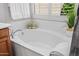 Bright bathtub with white tile, chrome fixtures, and a garden window letting in natural light at 3336 W Morse Dr, Anthem, AZ 85086
