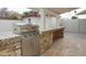 A stainless steel gas grill sits on an outdoor kitchen island with stone accents and tile countertop at 4115 W Sierra St, Phoenix, AZ 85029