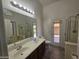 Bright bathroom with double sinks, wood-look tile flooring, a glass-enclosed shower, and exit to the backyard at 4255 E Rock Dr, San Tan Valley, AZ 85143