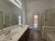 Bright bathroom featuring double sinks, wood-look tile flooring, and a glass-enclosed shower near the exit to the backyard at 4255 E Rock Dr, San Tan Valley, AZ 85143