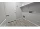 A practical laundry room with wood-look tile flooring, white walls, storage shelf and access to exterior at 4255 E Rock Dr, San Tan Valley, AZ 85143